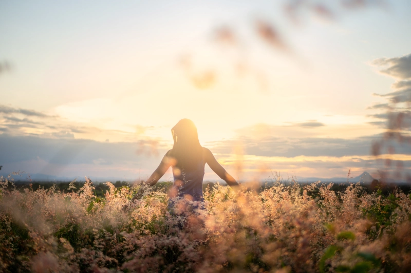 Femme marchant dans un champ au coucher de soleil